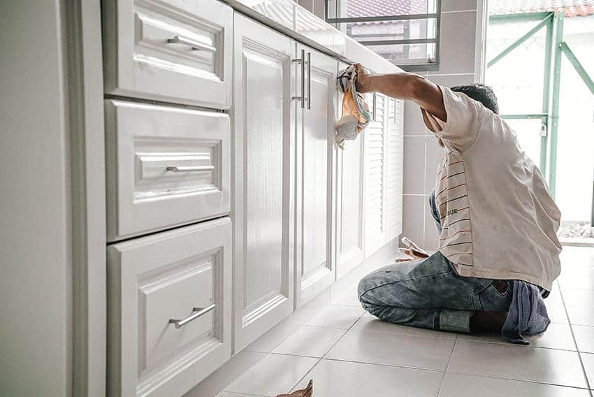 how to fix worn spots on kitchen cabinets - man fixing worn spots in cabinet