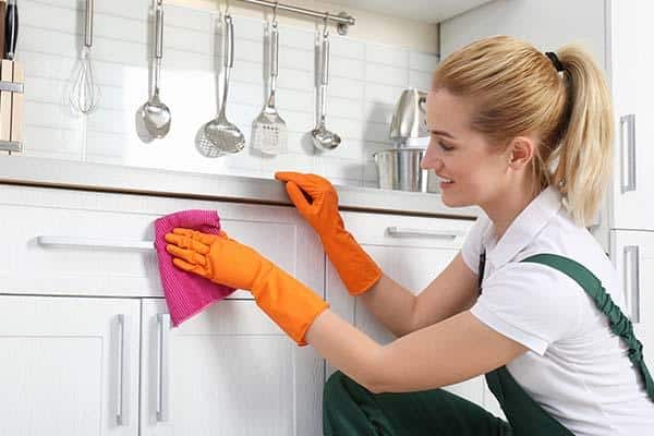 how to fix worn spots on kitchen cabinets - woman fixing worn cabinet