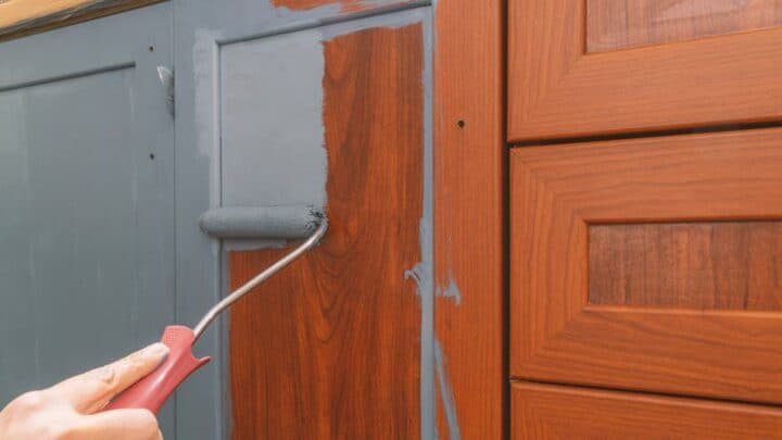 how to fix worn spots on kitchen cabinets - person painting cabinets to hide scratches